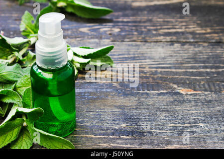 Peppermint essential oil in a glass bottle  on wooden background Stock Photo
