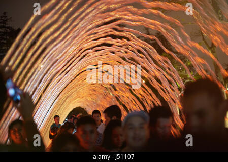 Lima, Peru - April 23, 2017: People walk under colorful fountain water in park. Stock Photo