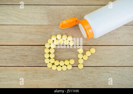 Yellow pills forming shape to Cr alphabet on wood background Stock Photo