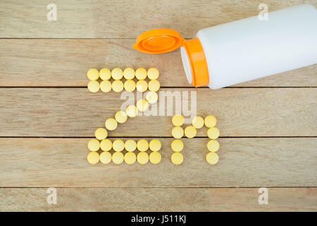 Yellow pills forming shape to Zn alphabet on wood background Stock Photo