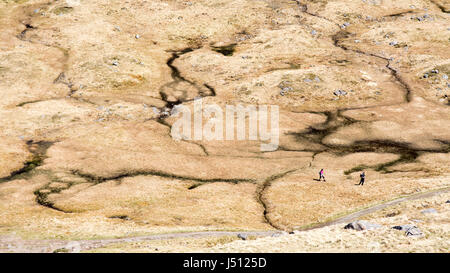 Hikers cross boggy ground at a mountain  watershed, seen from Ben Arthur, "The Cobbler", a mountain in the West Highlands of Scotland. Stock Photo