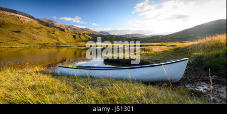 A small rowing boat on the shores of Lochan an Iasgair lake in the valley floor of Glen Torridon, under the Torridon Hills mountains of the West Highl Stock Photo