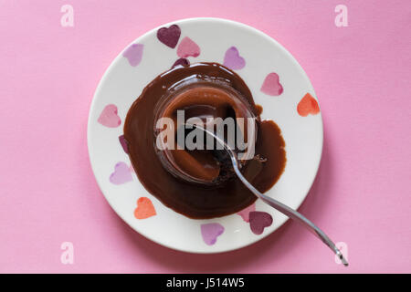 Getting ready to eat M&S melting chocolate dome from dessert menu - on hearts plate set on pink background Stock Photo