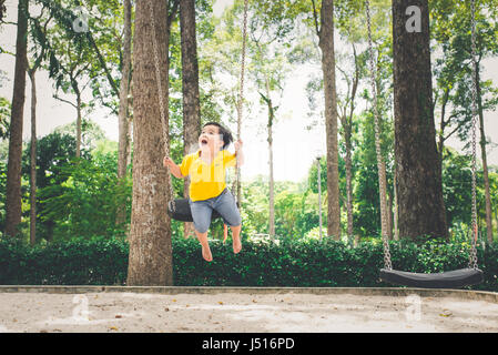 Cute Little Asian Boy In Adult Clothes Sitting On Beanbag Against Green 