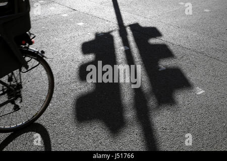 Shadow of traffic lights on tarmac road with cyclist bicycle wheel in a Clerkenwell street in London UK   KATHY DEWITT Stock Photo