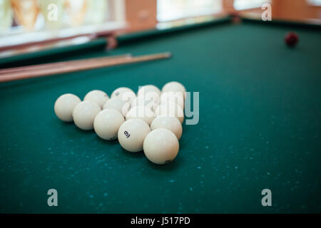 Billiard balls and two Cues in the form of a triangle on the billiard table are ready for the game. Stock Photo