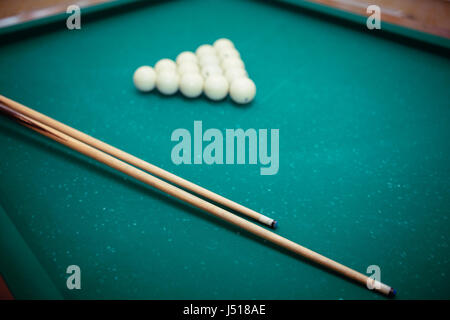 Billiard balls and two Cues in the form of a triangle on the billiard table are ready for the game. Stock Photo