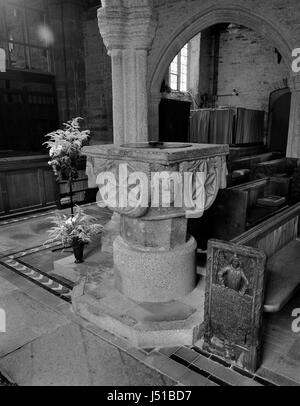 St Nonna's Church, Altarnun, Cornwall: C12th Norman carved granite font and a C16th (1510-1530) wooden bench end carved & signed by Robert (sic) Daye. Stock Photo