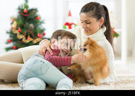 smiling family and dog sitting by Christmas tree Stock Photo