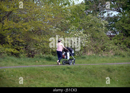 girl young mother pushing pram with baby on the Forth and Clyde canal towpath Glasgow Stock Photo