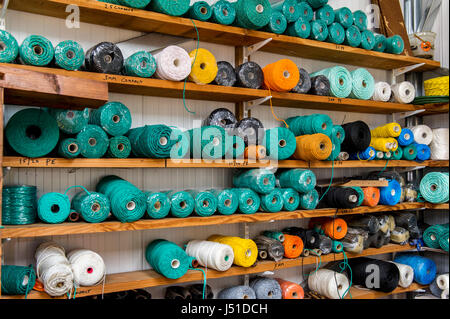 Reels of ropes and materials on shelves in the shed of a fishing net maker. Stock Photo