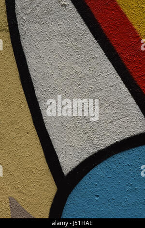 Closeup of colorful yellow, white, blue, and red graffiti on a cement wall Stock Photo