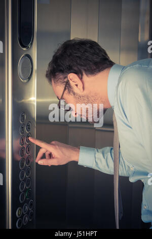 Businessman pressing the button in the elevator Stock Photo