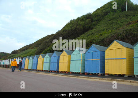 Bournemouth, UK -  13 May: A couple walk by an array of beach huts on the west side of Bournmouth beach. General view of the seaside town of  Bournemouth in Dorset, England. © David Mbiyu/Alamy Live News Stock Photo