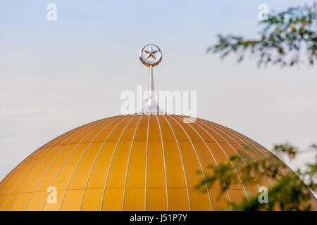 A silver star and crescent stands on top of the orange dome of a Muslim mosque in Petaling Jaya, Kuala Lumpur, Malaysia, Southeast Asia. Stock Photo