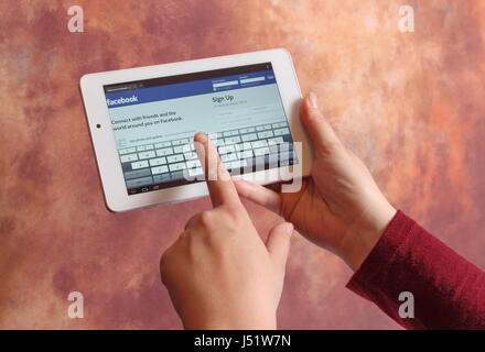 KRUSEVAC,SERBIA - MARCH 28 2015,Photo of hands holding tablet with Facebook log in page on screen, isolated on colorful background,Facebook is one of Stock Photo