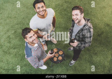 Overhead view of happy young friends drinking beer and making barbecue Stock Photo
