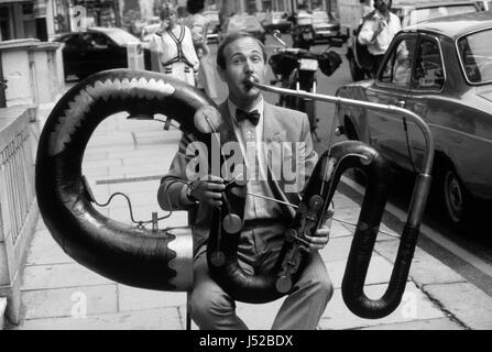 Professional serpent player Andrew van der Beek playing ‘The Anaconda’ outside Sotheby's in London August 1986. The instrument is the only known original example of a contra-bass serpent made by the brothers, Joseph and Richard Wood of Upper Heaton, Yorkshire, circa 1840.  Stock Photo