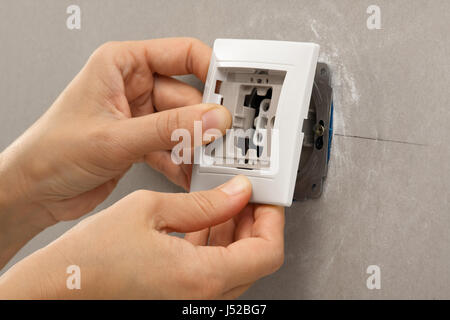 hands of electrician installing light switch on the wall from plasterboard Stock Photo