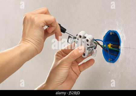 hands of electrician installing electrical socket with screwdriver Stock Photo