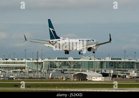 WestJet Airlines plane airplane Boeing 737 landing Vancouver International Airport Canadian airports air travel passenger jet Stock Photo
