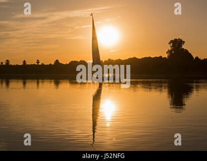 Traditional egyptian felluca sailing boat on river Nile in silhouette at dusk sunset Stock Photo