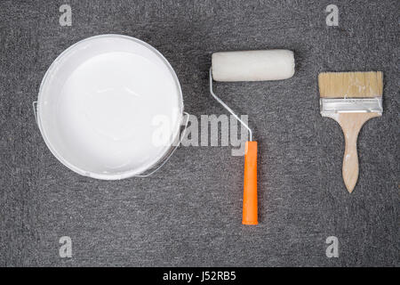 Top view of white plastic bucket and brush, roller, on the floor. Stock Photo