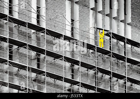 Construction work in the city, one worker walking on scaffolds Stock Photo