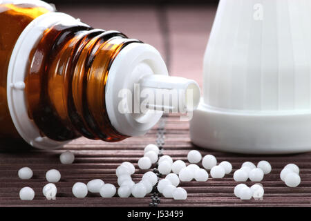 scattered homeopathic pills falling out of upset vial Stock Photo