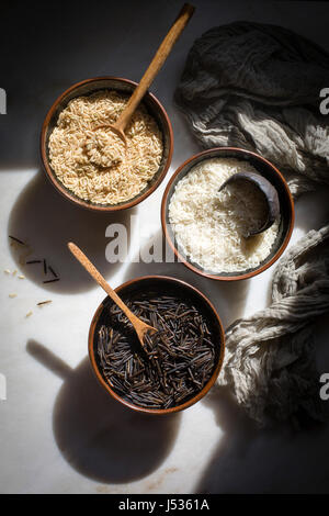 Grains - Wild rice,Brown rice and White basmati rice in separate bowls on a marble table on top down shot Stock Photo