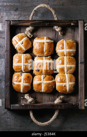 Hot cross buns in wooden tray over old texture metal background. Top view, space. Easter baking. Stock Photo