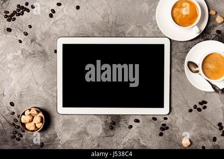 Tablet and coffee on grey stone background. Top view. Flat lay style. Stock Photo