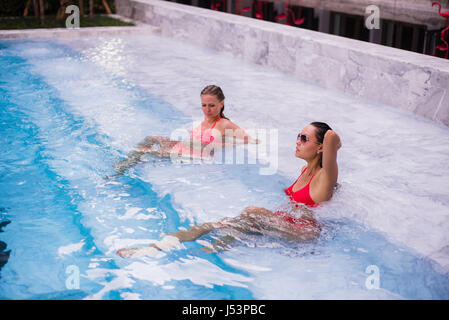 Young women relaxing by the pool Stock Photo