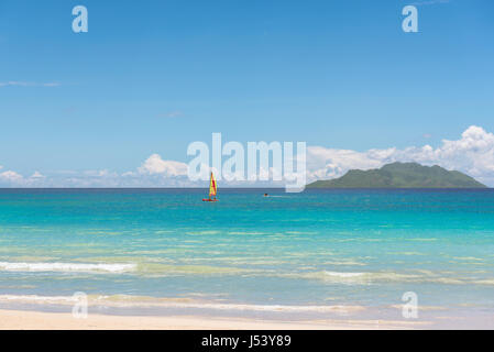 Tropical beach, sailing boat and island in the ocean. Stock Photo