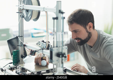 Young designer engineer using a 3D printer in the laboratory and studying a product prototype, technology and innovation concept Stock Photo