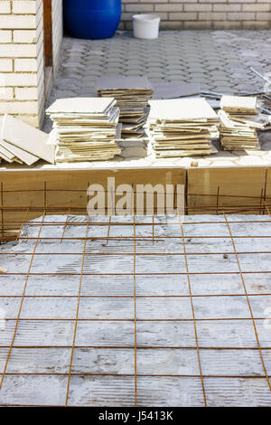 armature grids in a concrete floor in front of broken out ceramic plates Stock Photo