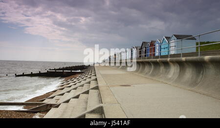 Beach huts on seafront in Suffolk,with concrete sea defences in front Stock Photo