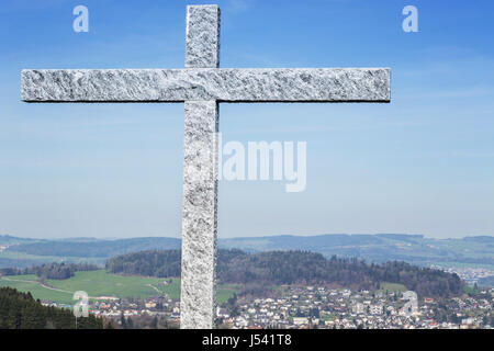 granite cross in front of green landscape of village in st. gallen, switzerland Stock Photo