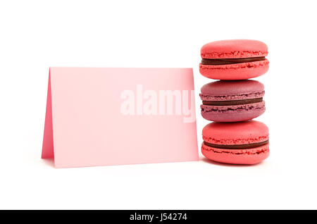 Stack of colorful traditional French macaroon pastry cookies (macarons, macaroni) with pink paper sign isolated on white background, close up, low ang Stock Photo