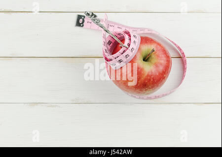 red apple with measuring tape and fork on wooden background, diet concept Stock Photo