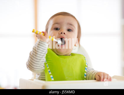 Happy baby boy spoon eats itself Stock Photo