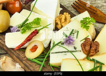 Refreshments from different types of cheese. Healthy breakfast of dairy products. Sliced cheeses on a wooden table Stock Photo