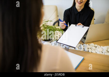 Two happy business women talking and signing document Stock Photo