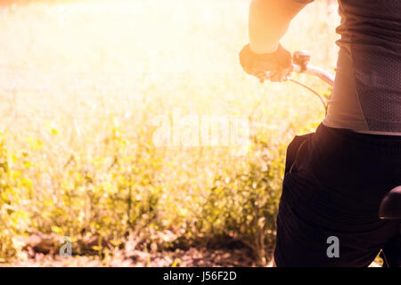 back of cyclist who is resting in the evening sunshine at green nature Stock Photo