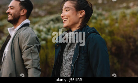 Beautiful asian woman walking with her boyfriend in countryside. Smiling couple hiking in countryside. Stock Photo