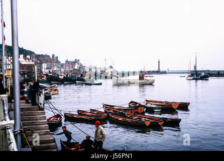Vintage image of Whitby harbour, North Yorkshire, England, UK taken in August 1963 showing fishing boats moored and fishermen working. Stock Photo