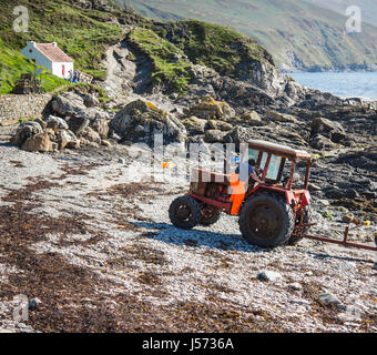 Unusual view of Niarbyl cottage: farmer with his old Belarus tractor. isle of man Stock Photo