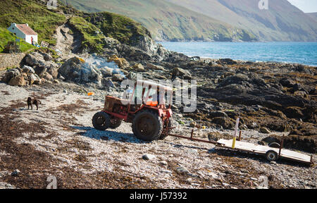 Fisherman is lining up to pull his boat out of water with his old Belarus tractor Stock Photo