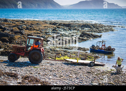 Fisherman is lining up to pull his boat out of water with his old Belarus tractor Stock Photo