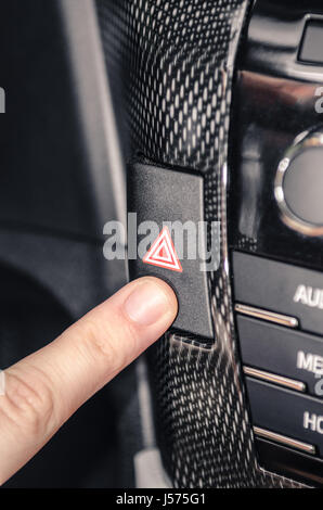 Finger pressing the car warning flashing button. Harzard switch. Stock Photo